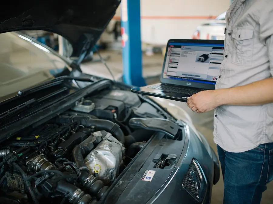 Mechanic reading fault codes on a laptop connected to a car