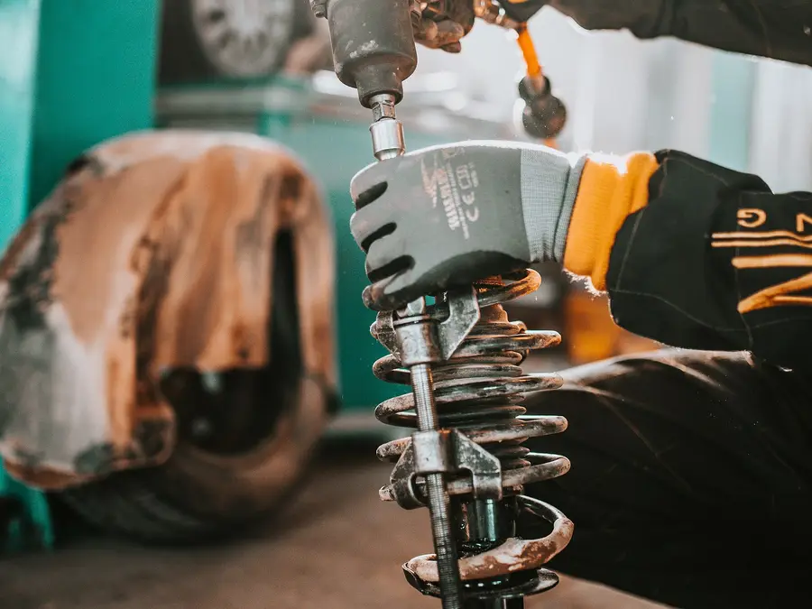 Gloved hands fitting a coil spring and shock absorber